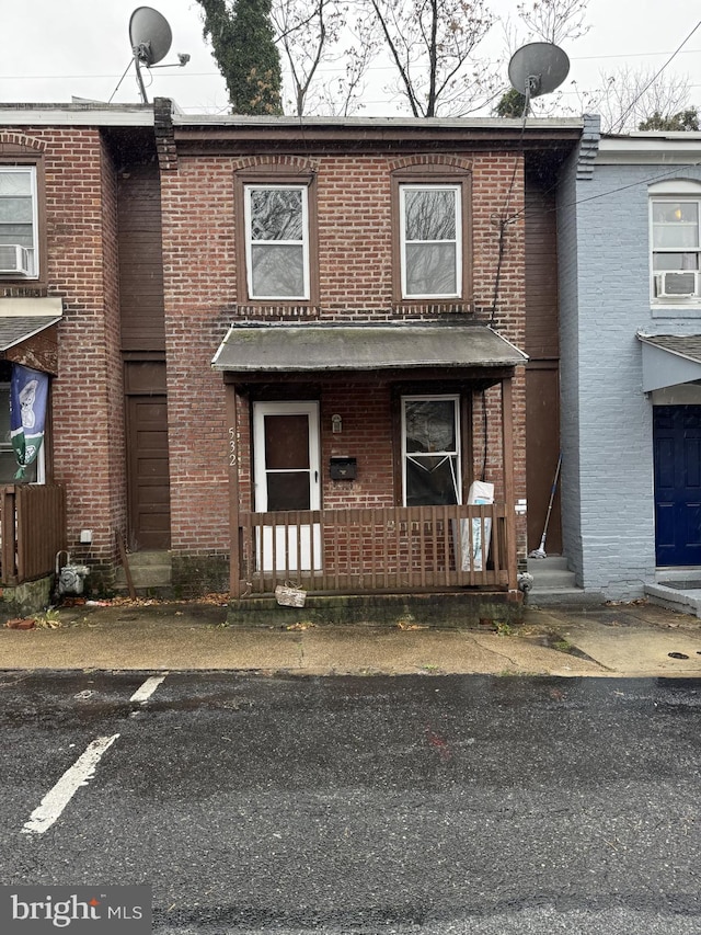 view of front facade featuring a porch, cooling unit, and brick siding