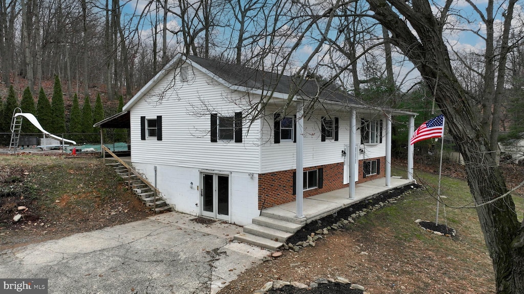 view of front of house featuring a patio area, stairs, french doors, and brick siding