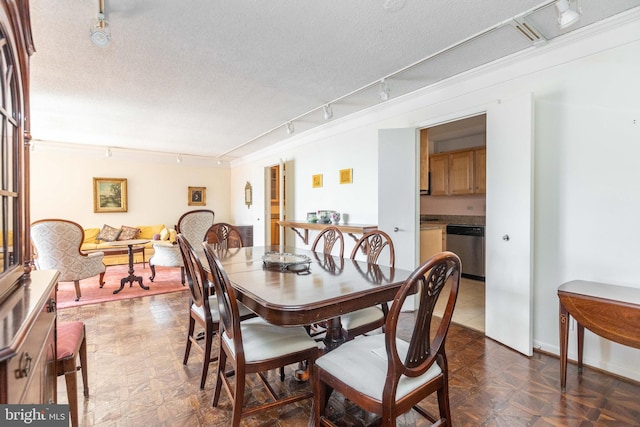 dining space with rail lighting and a textured ceiling