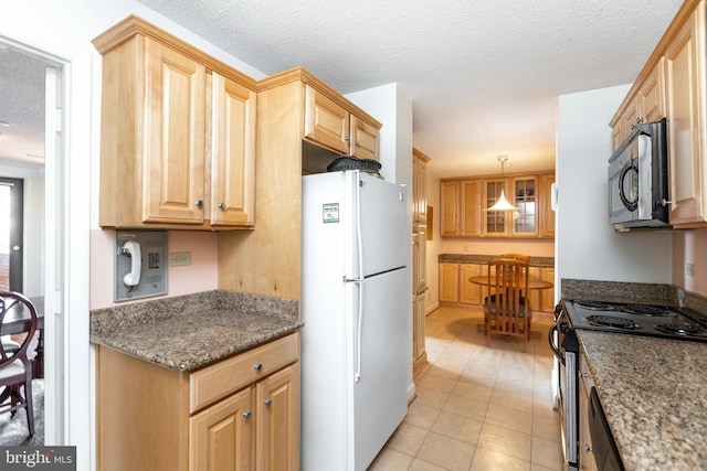 kitchen featuring light brown cabinets, a textured ceiling, dark stone counters, appliances with stainless steel finishes, and light tile patterned flooring