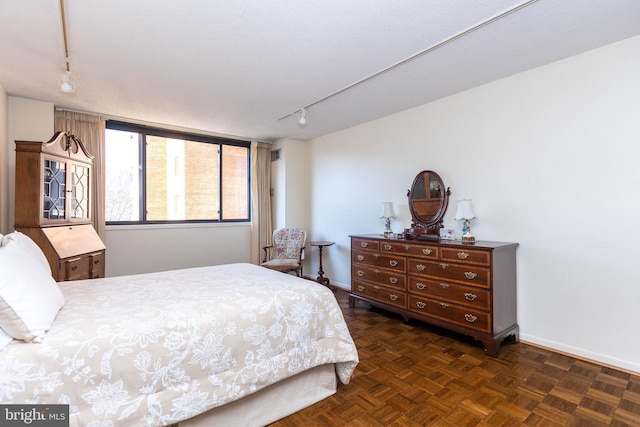 bedroom with track lighting and baseboards