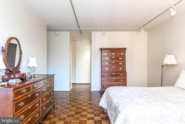 bedroom featuring track lighting and a textured ceiling