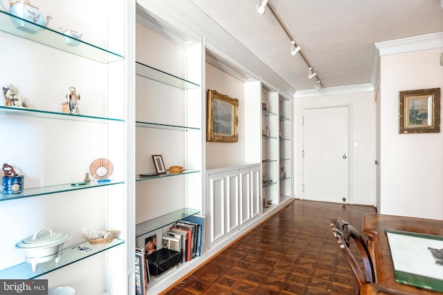 hallway with track lighting, built in features, a textured ceiling, and ornamental molding