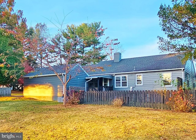 ranch-style house featuring a fenced front yard, a chimney, a front lawn, and roof with shingles