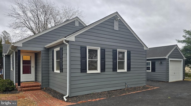 view of home's exterior featuring driveway, a detached garage, and an outdoor structure