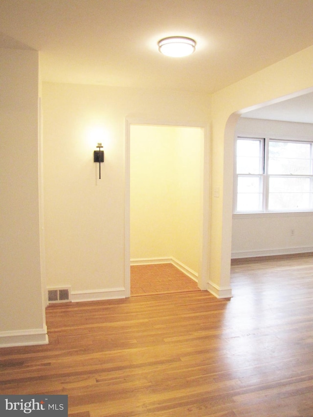 unfurnished room featuring visible vents, baseboards, and wood finished floors