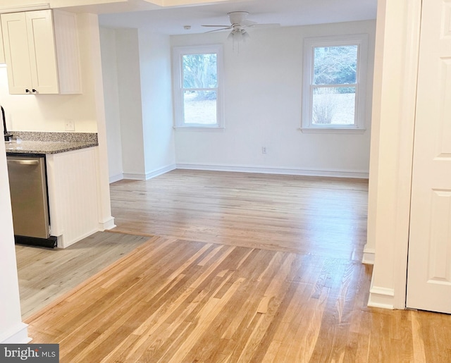 unfurnished living room with baseboards, a healthy amount of sunlight, a ceiling fan, and light wood-style floors