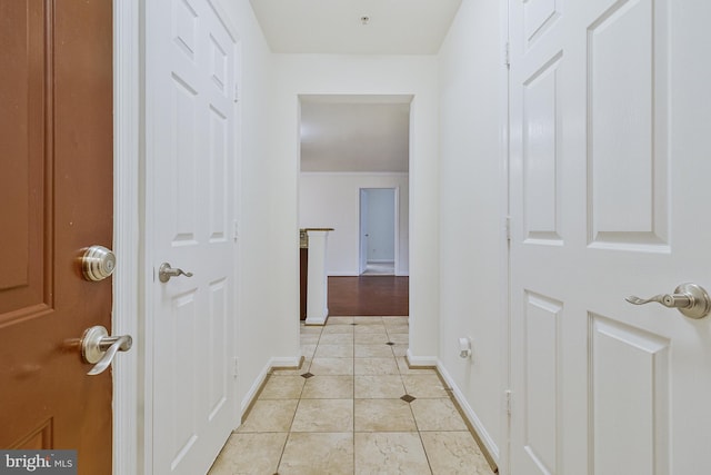 hall featuring light tile patterned flooring and baseboards