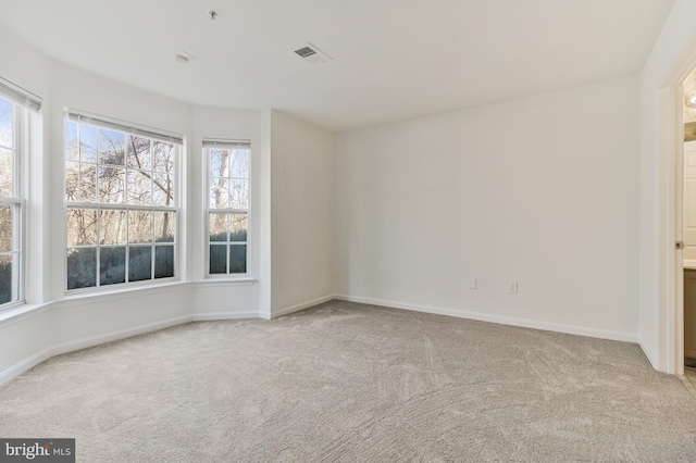 spare room featuring carpet floors, visible vents, and baseboards