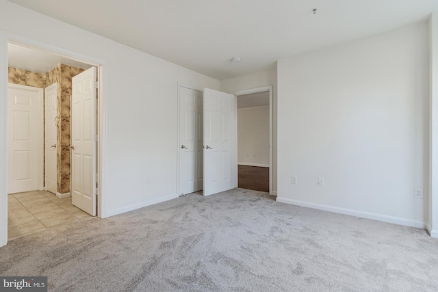 unfurnished bedroom featuring connected bathroom, baseboards, and carpet flooring