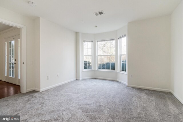 carpeted empty room featuring visible vents and baseboards