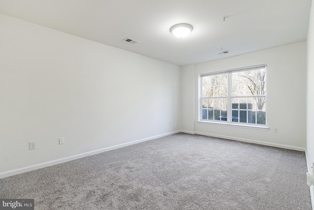 spare room with carpet floors, visible vents, and baseboards