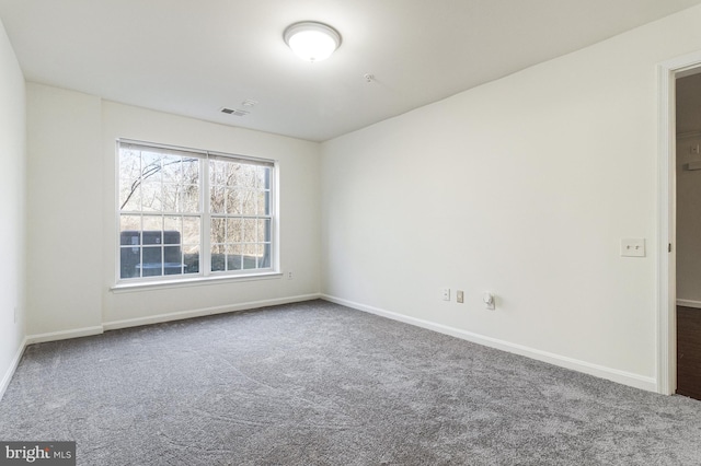 carpeted empty room featuring baseboards and visible vents