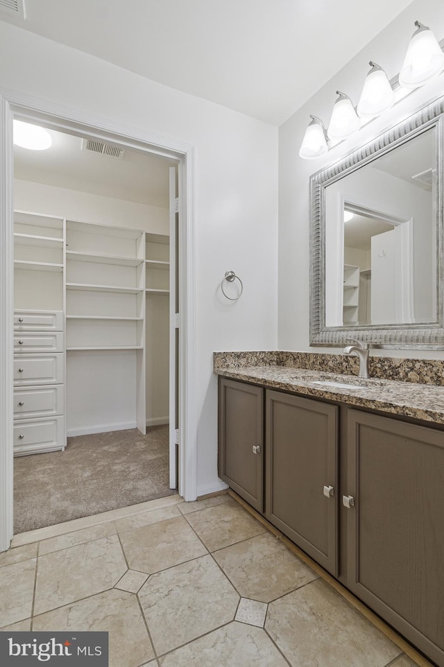 bathroom featuring visible vents, a spacious closet, and vanity