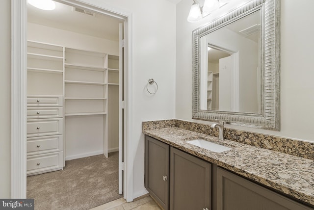 bathroom featuring a spacious closet, vanity, and visible vents