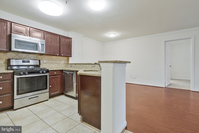 kitchen with crown molding, stainless steel appliances, tasteful backsplash, a sink, and a peninsula