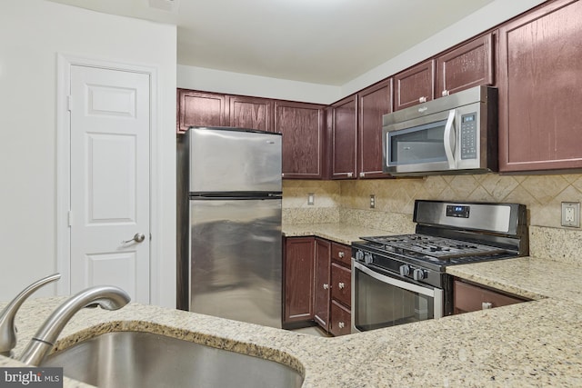 kitchen with light stone counters, a sink, visible vents, appliances with stainless steel finishes, and tasteful backsplash