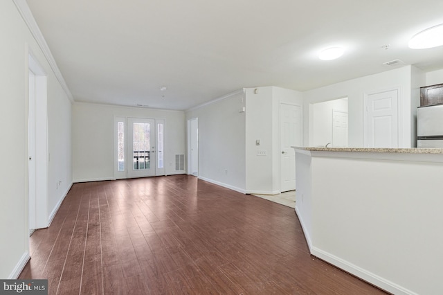 unfurnished living room with crown molding, wood finished floors, visible vents, and baseboards