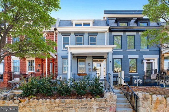 view of front of property featuring a porch, mansard roof, and brick siding