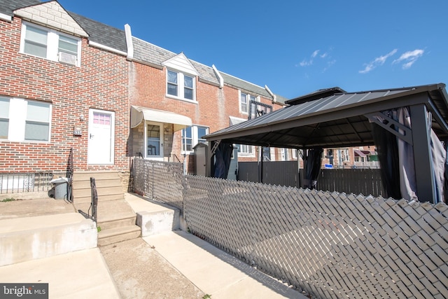 exterior space with a gazebo, a fenced front yard, and brick siding