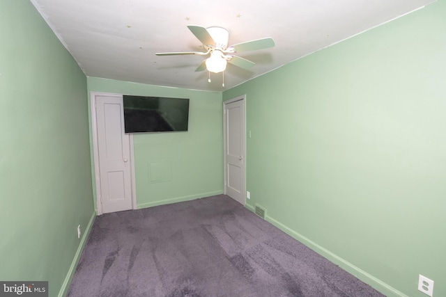 carpeted spare room with visible vents, baseboards, and a ceiling fan