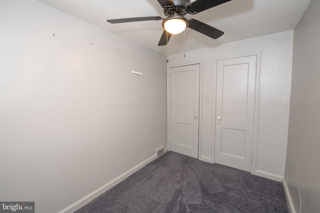 unfurnished bedroom featuring baseboards, dark carpet, and ceiling fan