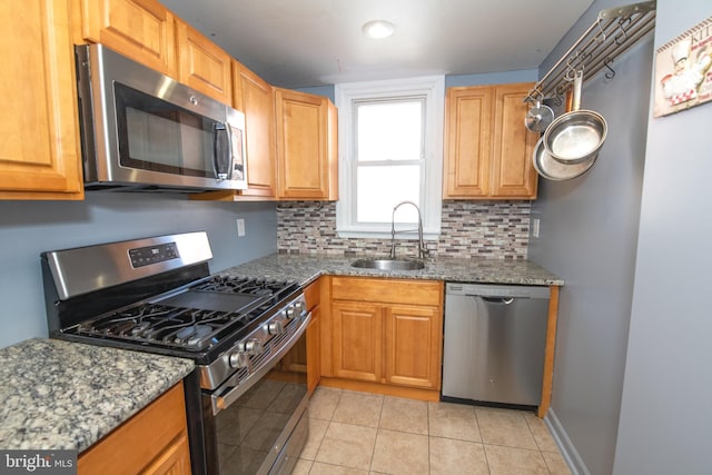 kitchen featuring stainless steel appliances, tasteful backsplash, light tile patterned flooring, and a sink