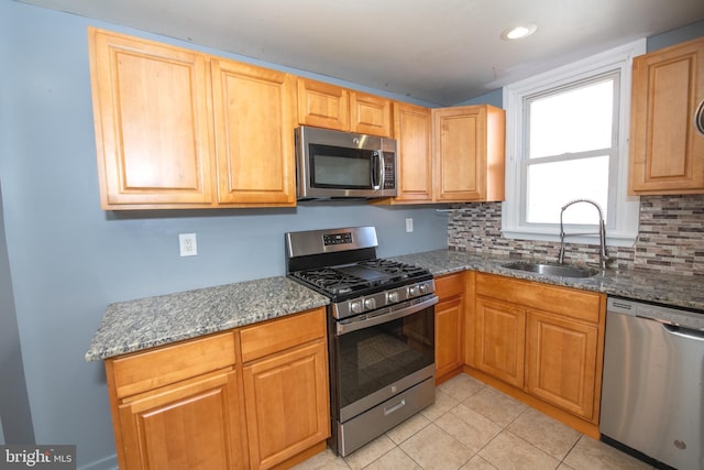 kitchen featuring light tile patterned floors, decorative backsplash, stainless steel appliances, and a sink