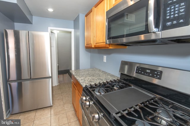 kitchen with light stone counters, light tile patterned floors, recessed lighting, appliances with stainless steel finishes, and brown cabinetry