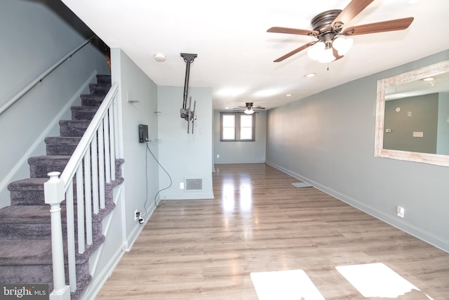 basement with light wood finished floors, visible vents, stairway, a ceiling fan, and baseboards