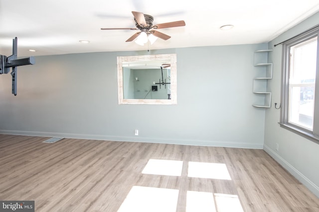 spare room featuring a ceiling fan, wood finished floors, visible vents, and baseboards