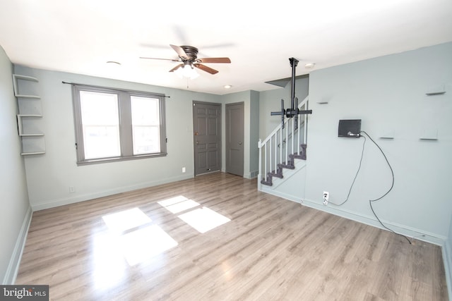 unfurnished room with ceiling fan, stairway, wood finished floors, and baseboards