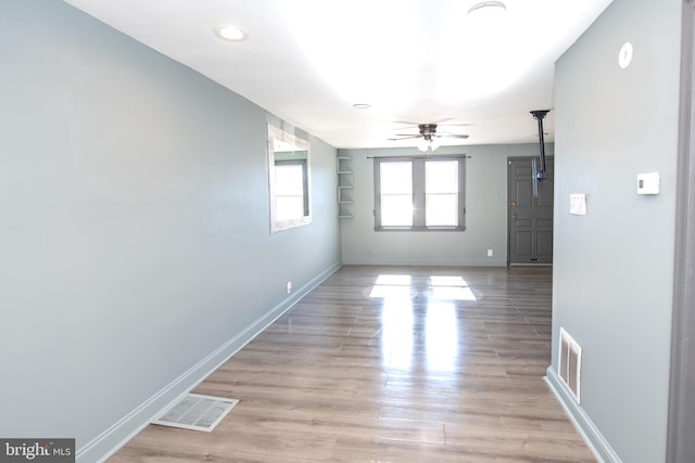 empty room featuring visible vents, ceiling fan, light wood-style flooring, and baseboards