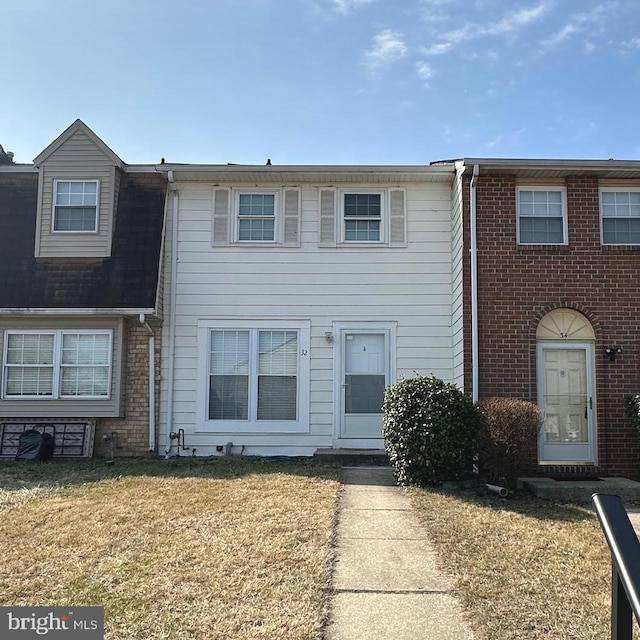 townhome / multi-family property with a front lawn and brick siding