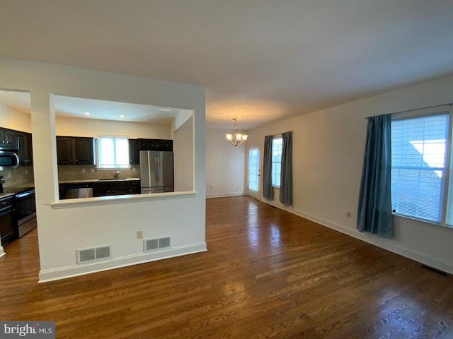 unfurnished living room with visible vents, an inviting chandelier, and a sink