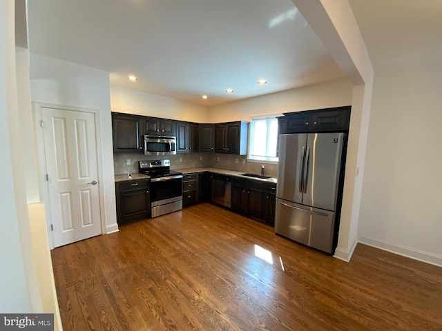 kitchen with dark wood-style floors, stainless steel appliances, light countertops, decorative backsplash, and baseboards