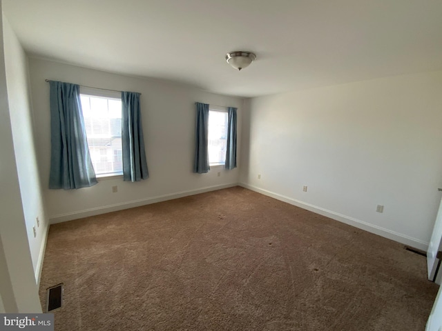 carpeted spare room with visible vents and baseboards