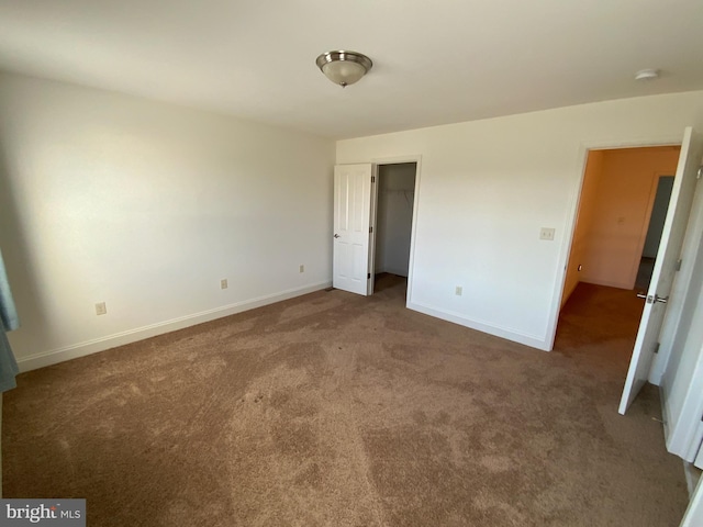 unfurnished bedroom featuring baseboards, carpet floors, and a spacious closet