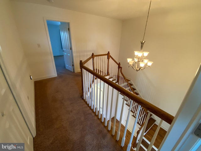 stairs with an inviting chandelier, carpet flooring, and baseboards