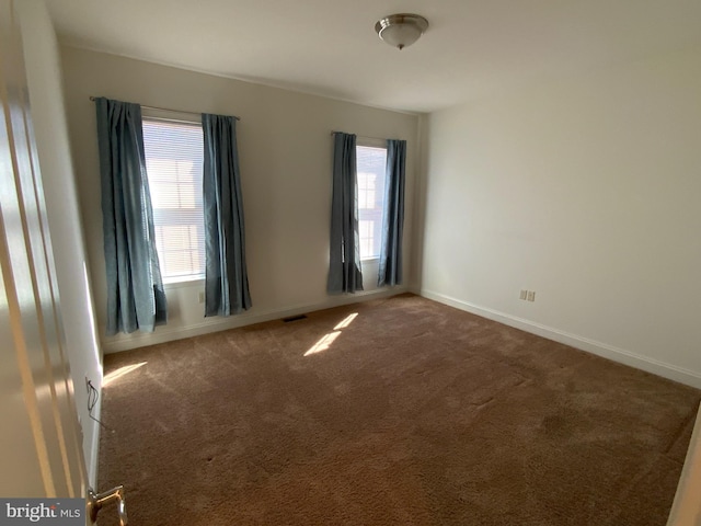 spare room featuring carpet and baseboards