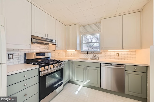 kitchen featuring under cabinet range hood, a sink, backsplash, appliances with stainless steel finishes, and light countertops