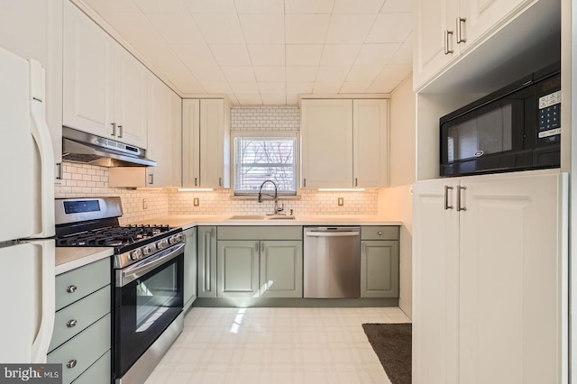 kitchen with under cabinet range hood, a sink, stainless steel appliances, light countertops, and decorative backsplash