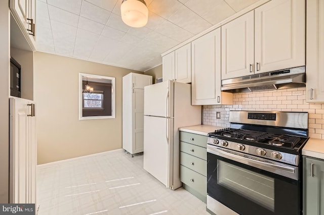 kitchen with backsplash, under cabinet range hood, light countertops, freestanding refrigerator, and stainless steel gas stove