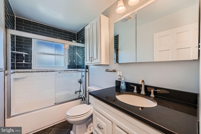 bathroom featuring vanity, visible vents, tile patterned flooring, toilet, and combined bath / shower with glass door