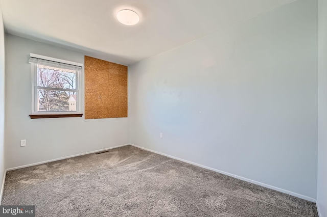 spare room featuring carpet flooring, baseboards, and visible vents