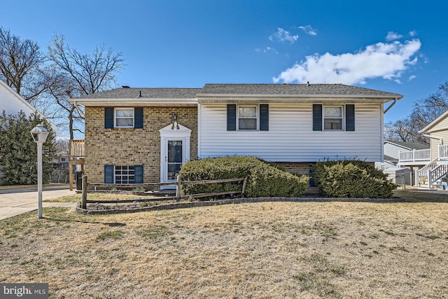 bi-level home with a front lawn, brick siding, and a shingled roof