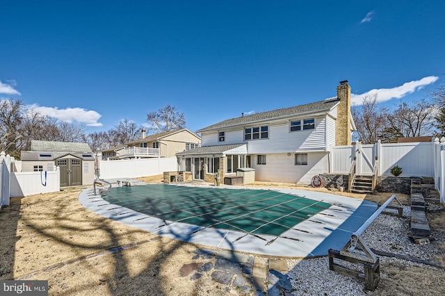 view of pool featuring a shed, an outdoor structure, a fenced backyard, and a gate