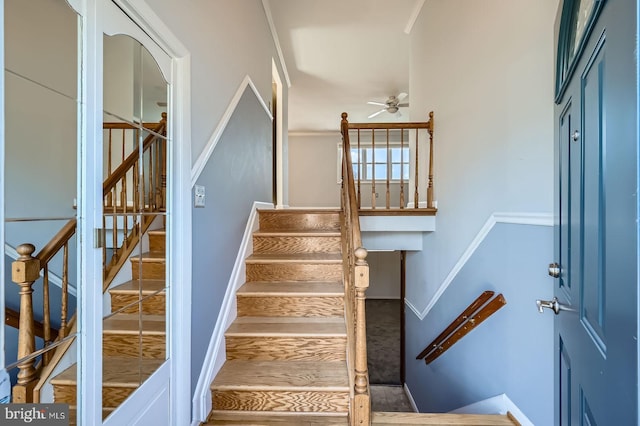 stairs featuring ceiling fan