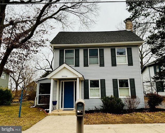 colonial home featuring a shingled roof and a chimney