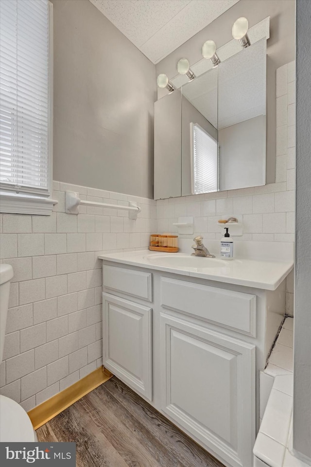 bathroom with a wealth of natural light, toilet, wood finished floors, and vanity